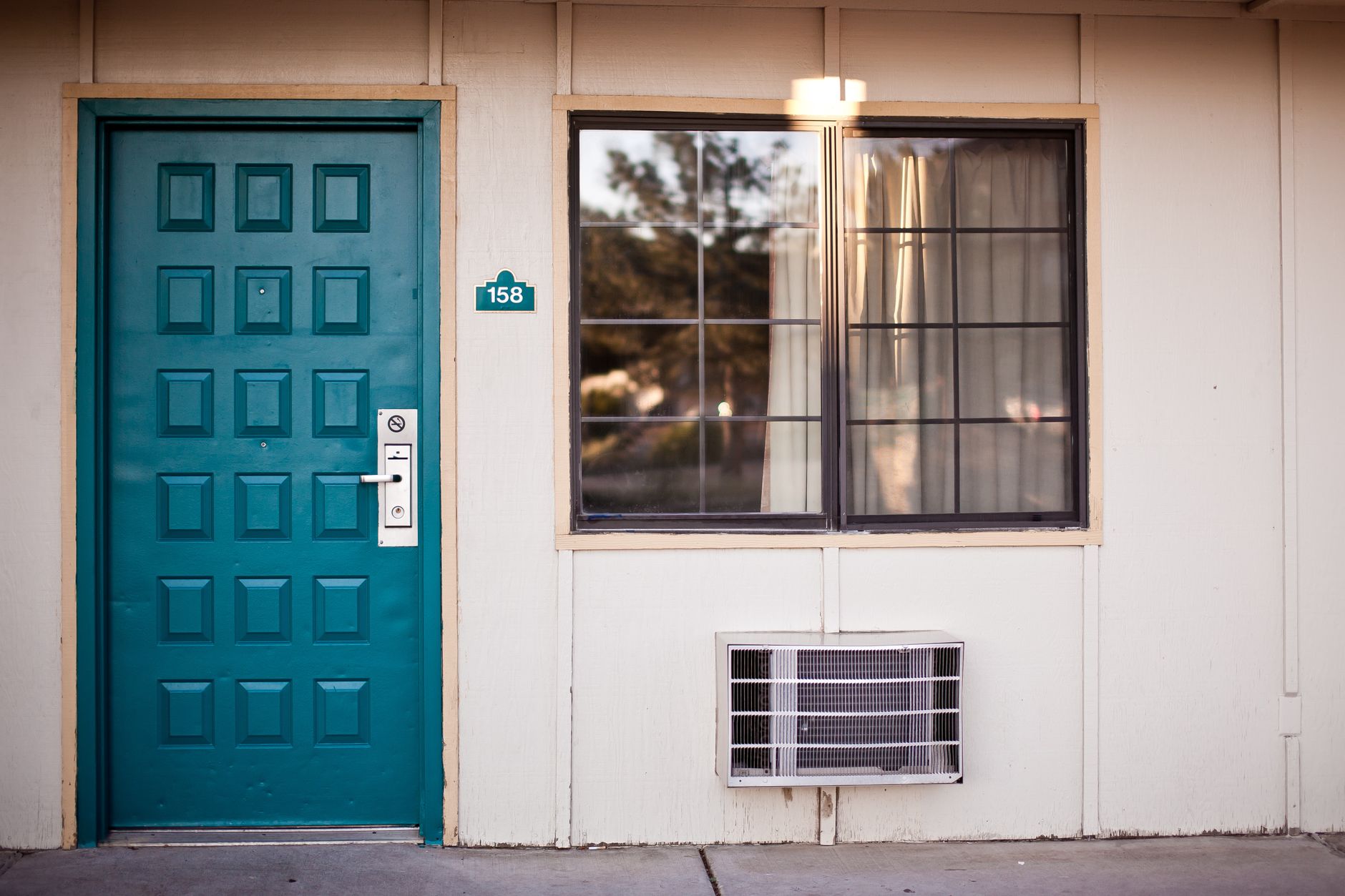 Front view of a teal door and window, typical motel exterior entrance facade